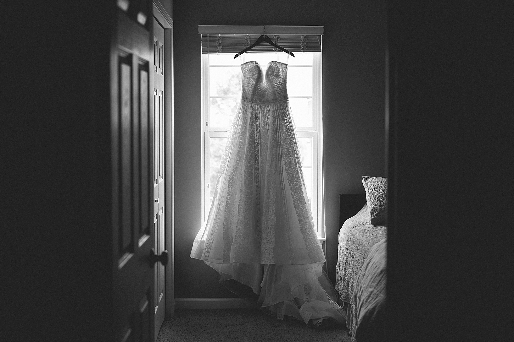 wedding gown hanging in front of window
