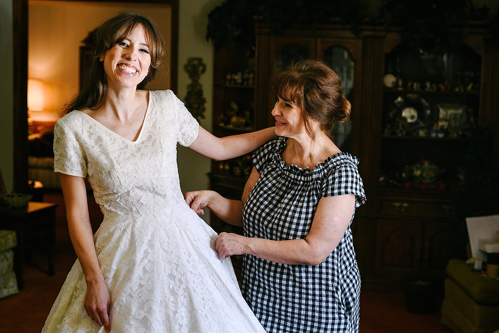 mother helping bride into her wedding dress