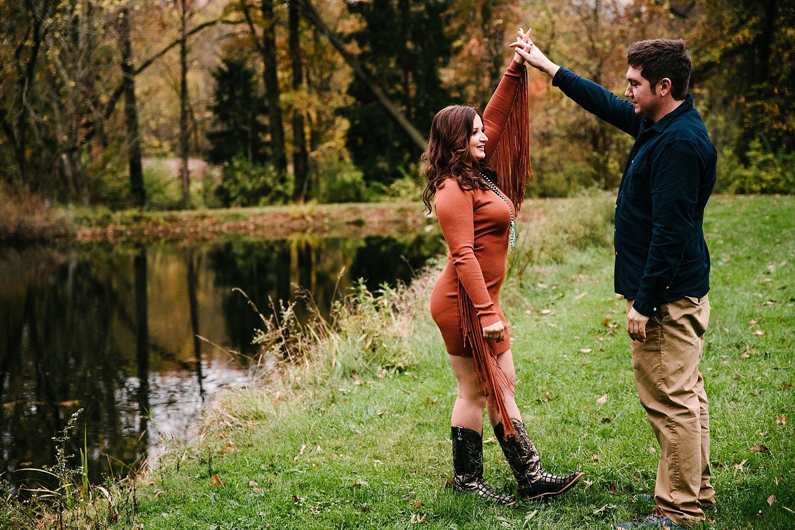 couple holding hands standing next to pond