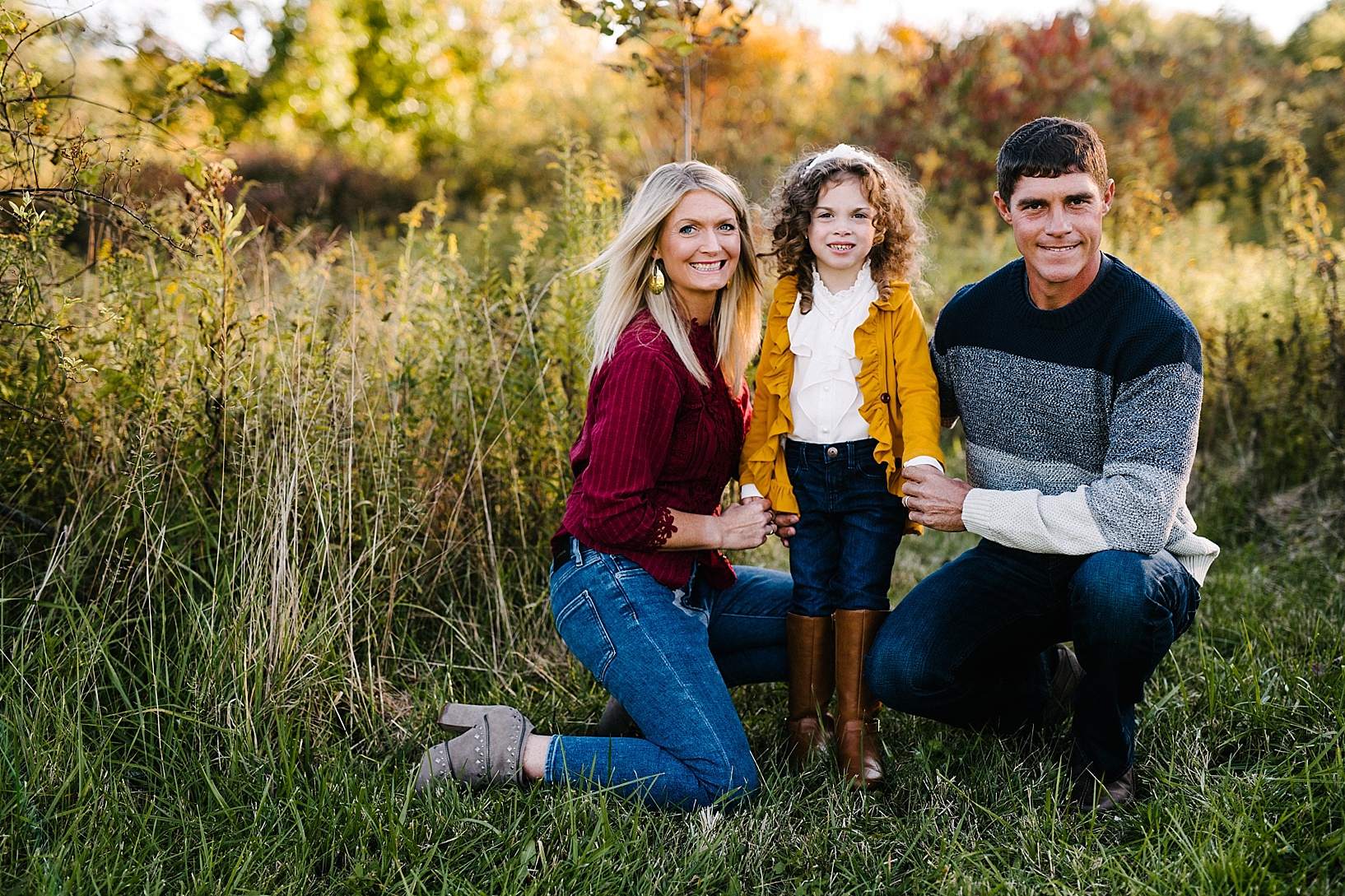 family with little girl kneeling in field
