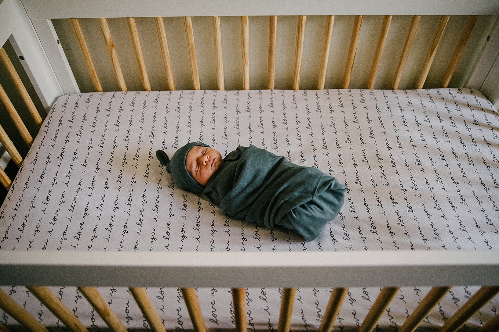newborn baby swaddled in blanket laying in crib