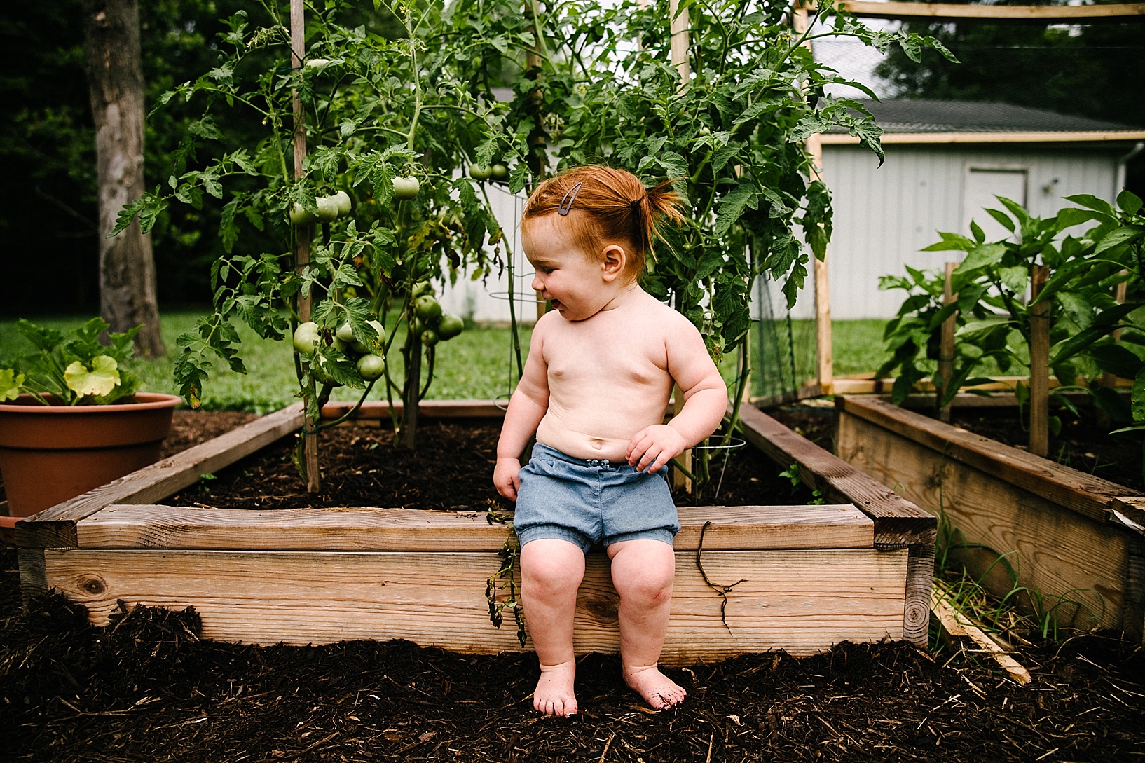 toddler sitting on wooden garden box