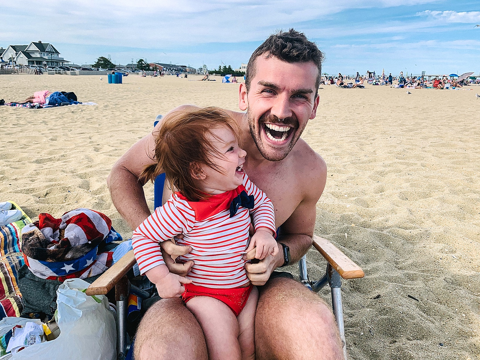 little girl sitting on uncle's lap at the beach