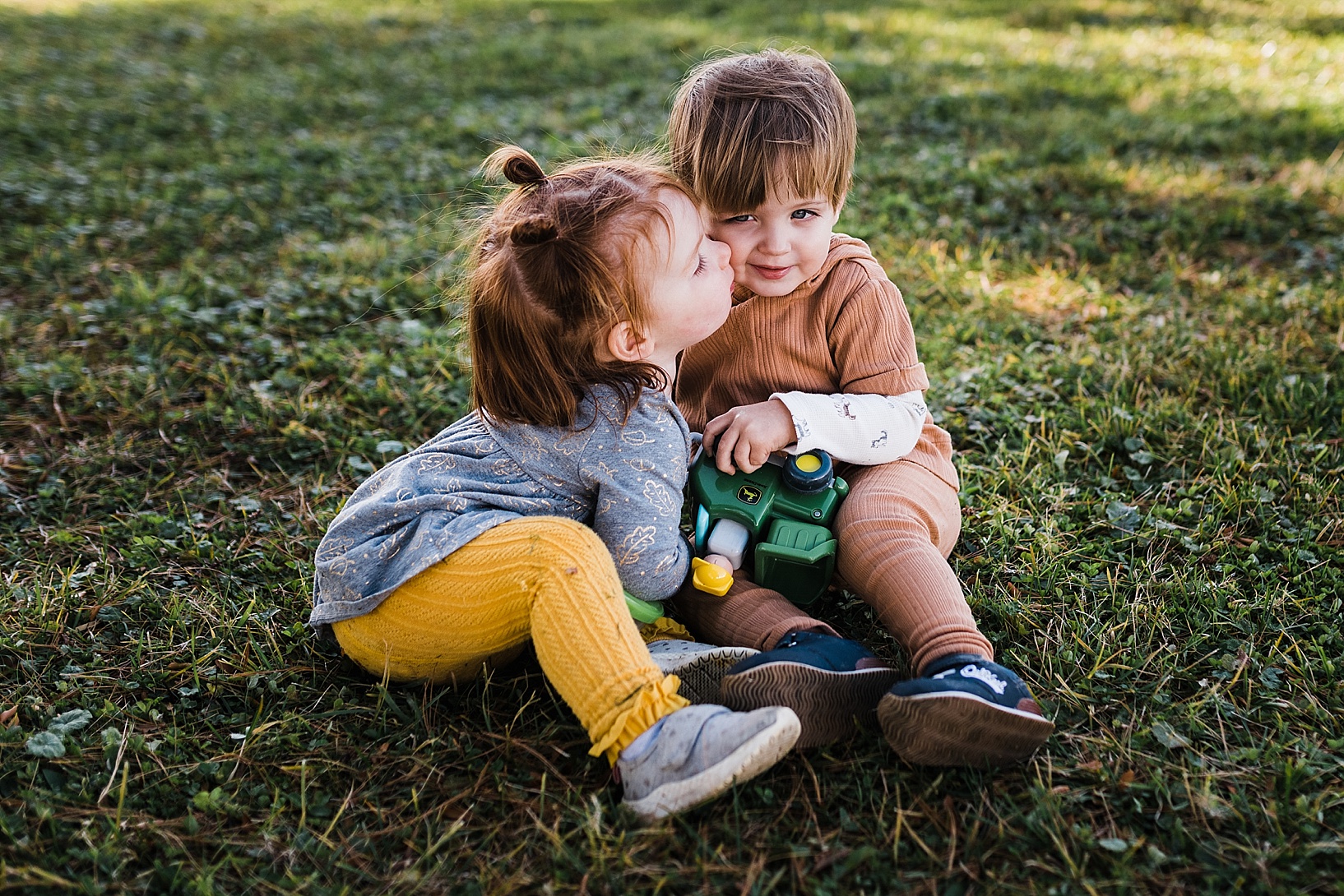 toddler girl with pigtails kissing little boy on the cheek