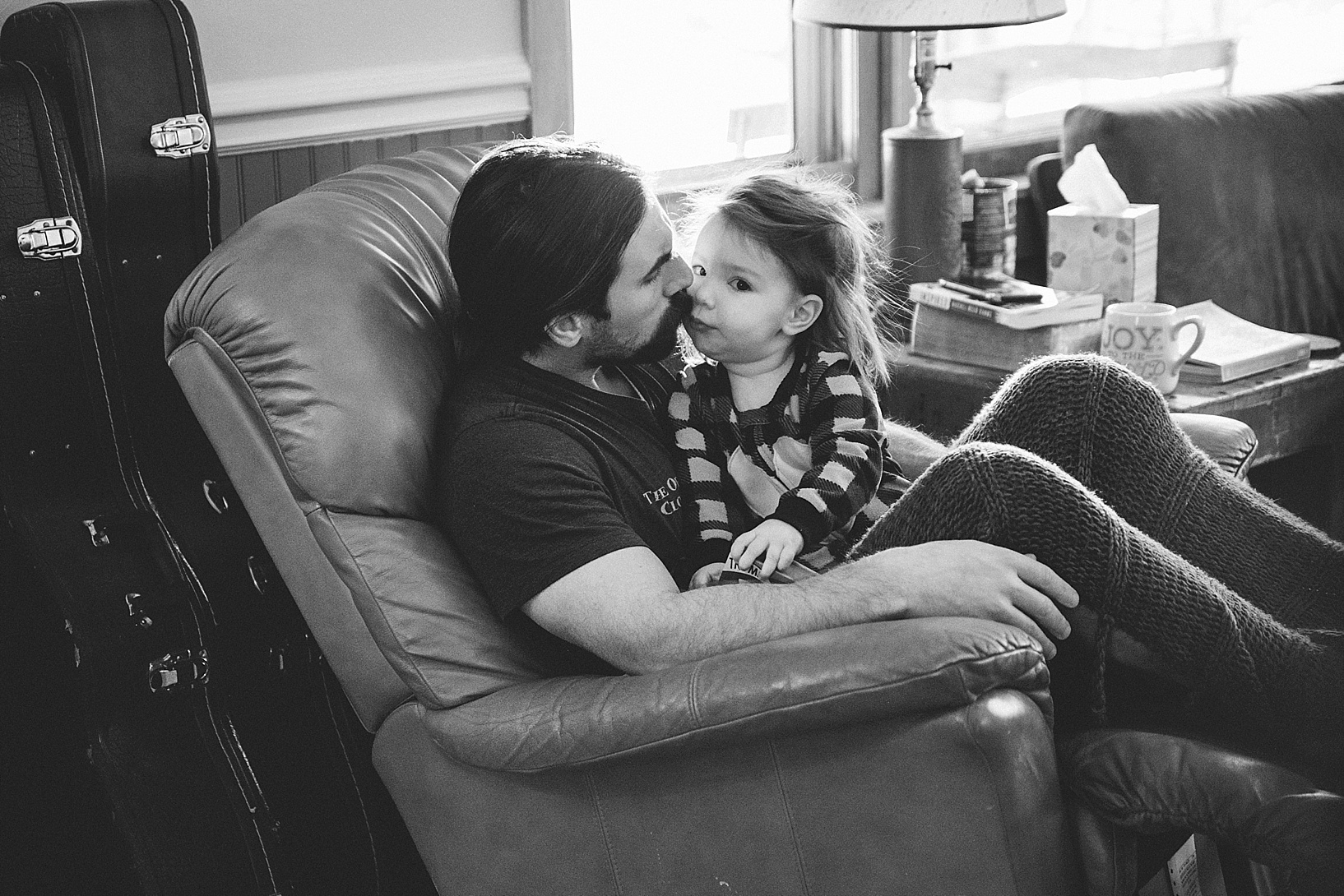 dad sitting in recliner kissing daughter on cheek