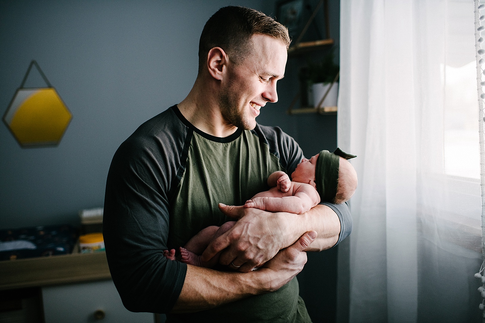 father holding newborn daughter in nursery