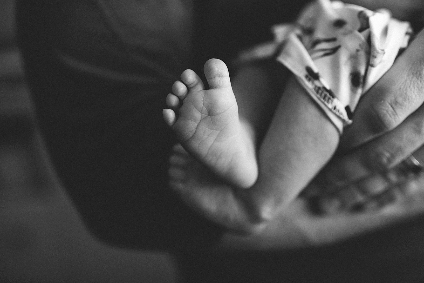 newborn baby feet held in father's arms
