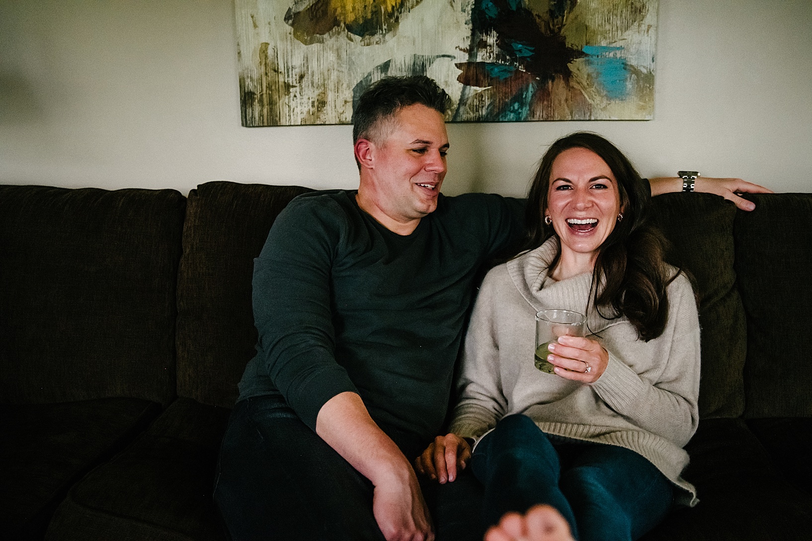 couple sitting on couch drinking cocktail and laughing