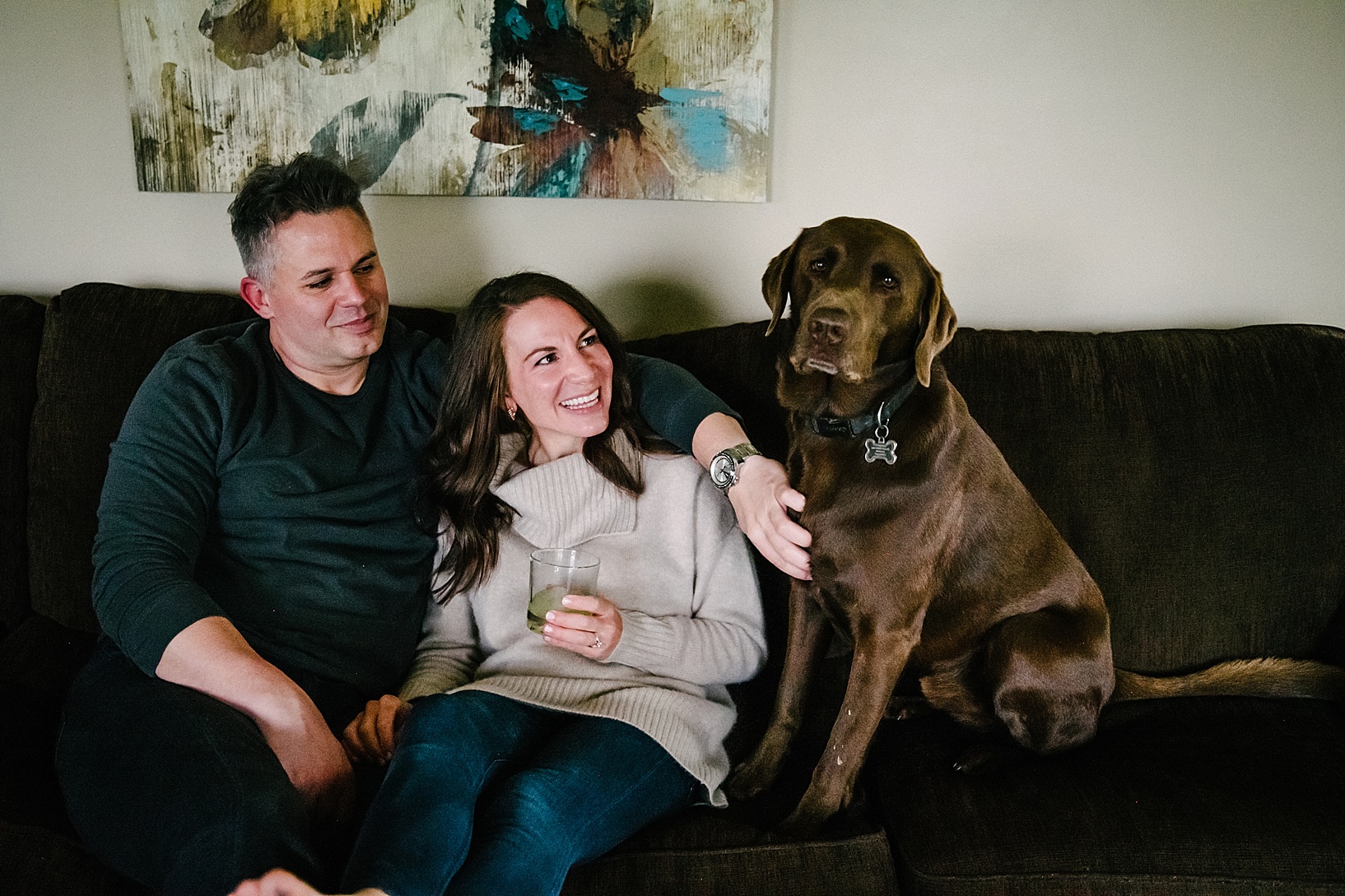 couple sitting on couch petting dog