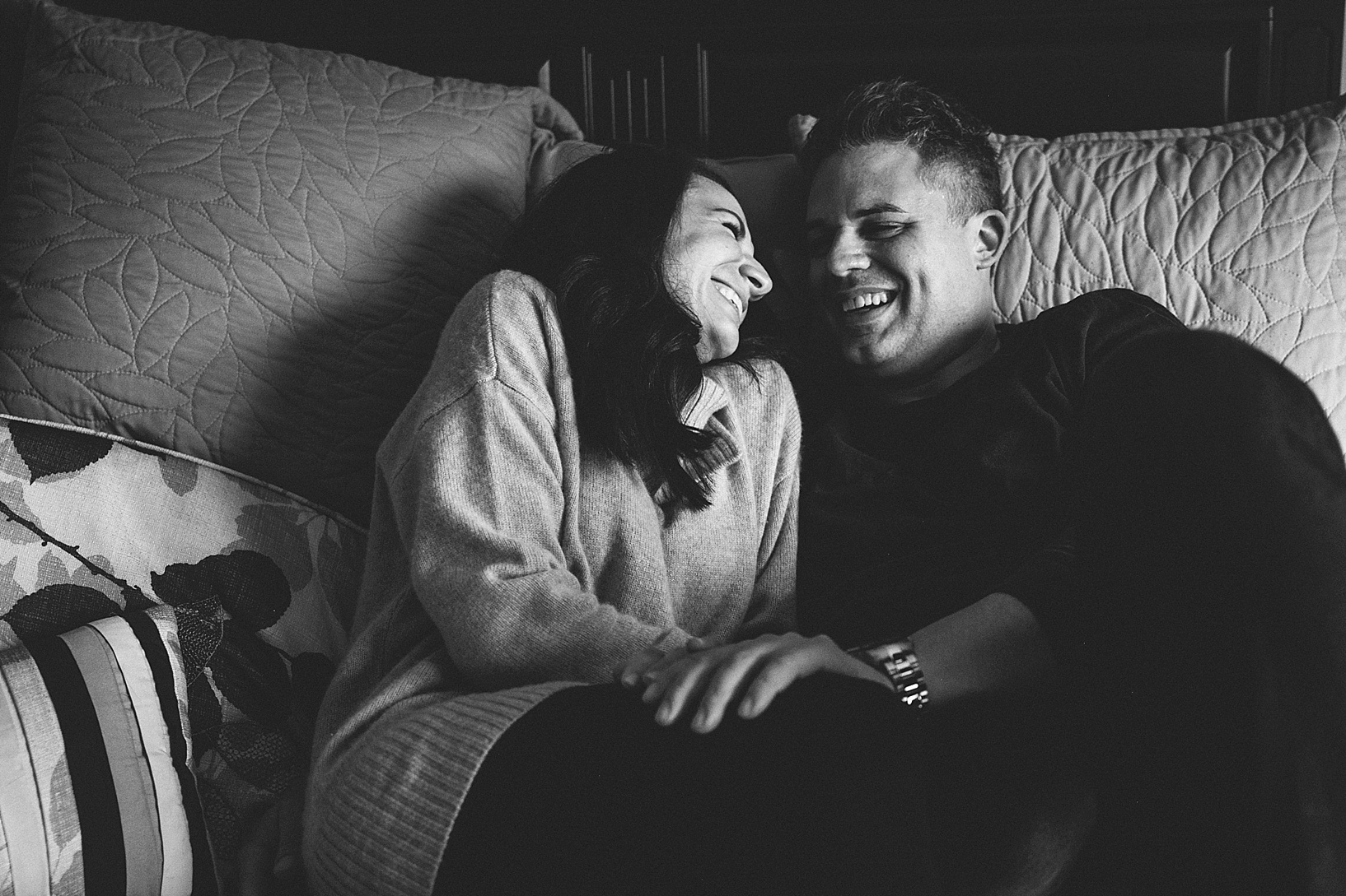 man and woman cuddling on bed and laughing