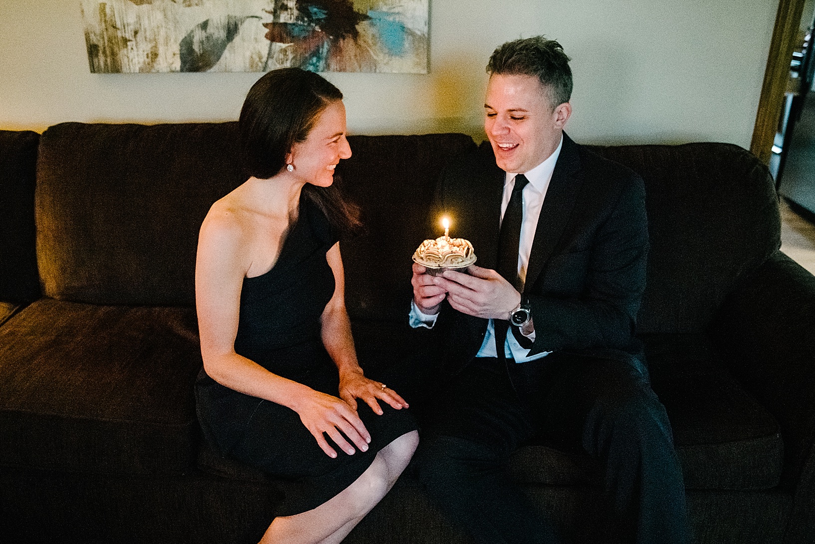 couple sitting on couch with cupcake and candle