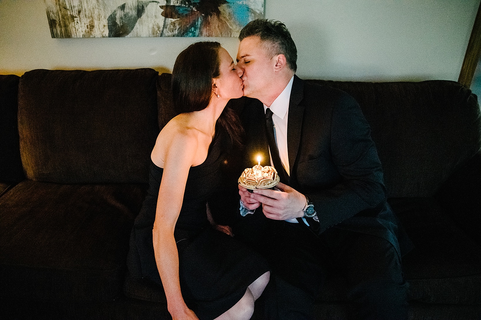 man kissing woman holding cupcake with candle