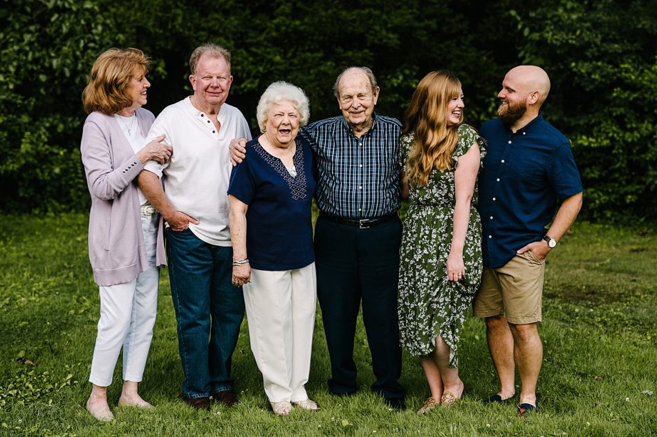 The whole family stands and poses with grandmother and grandfather in the middle.
