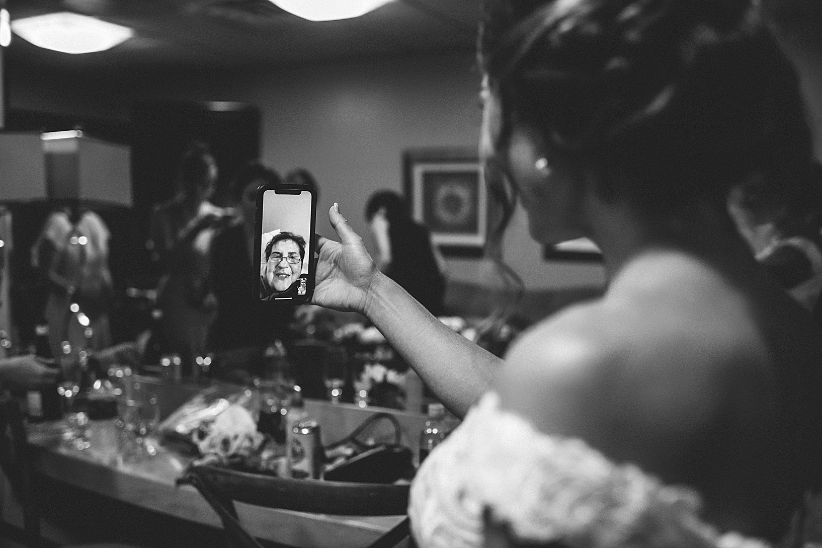 The bride facetiming with an older woman on an iphone in her wedding dress