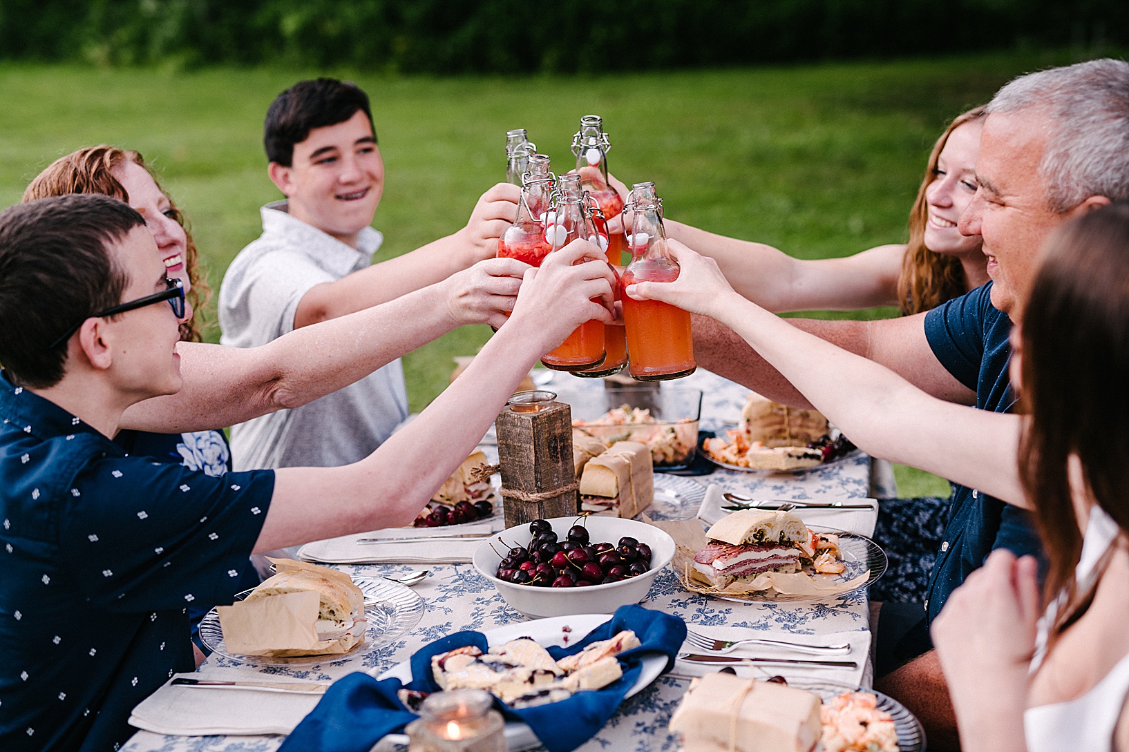 Family cheersing bottles during family Summer Picnic.