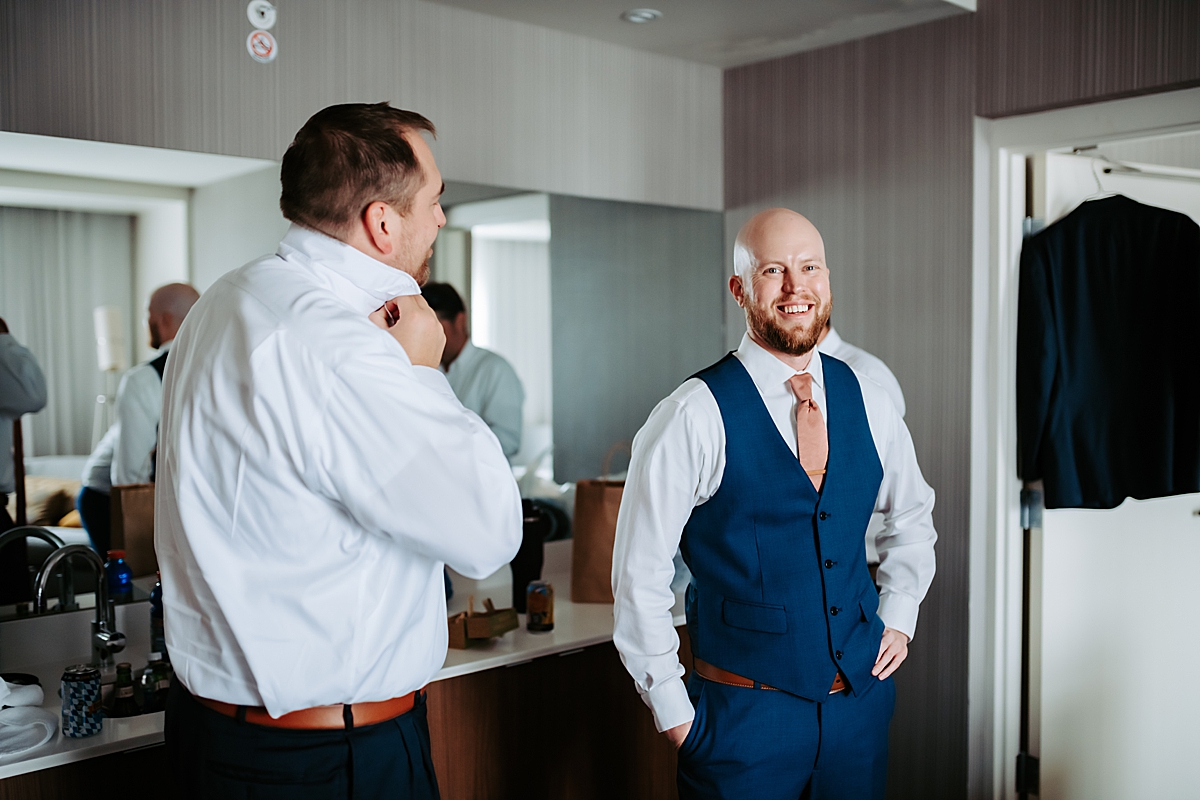 groom getting ready with best man in hotel room