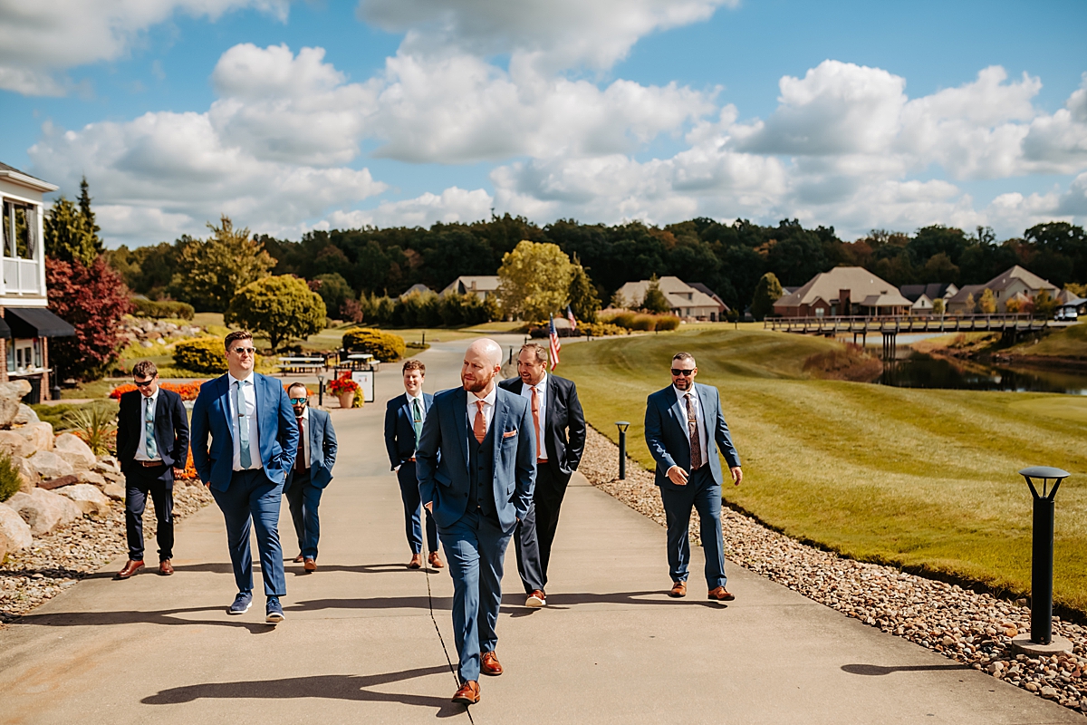 groom and groomsmen walking along path outside the Courtyard by Marriott 