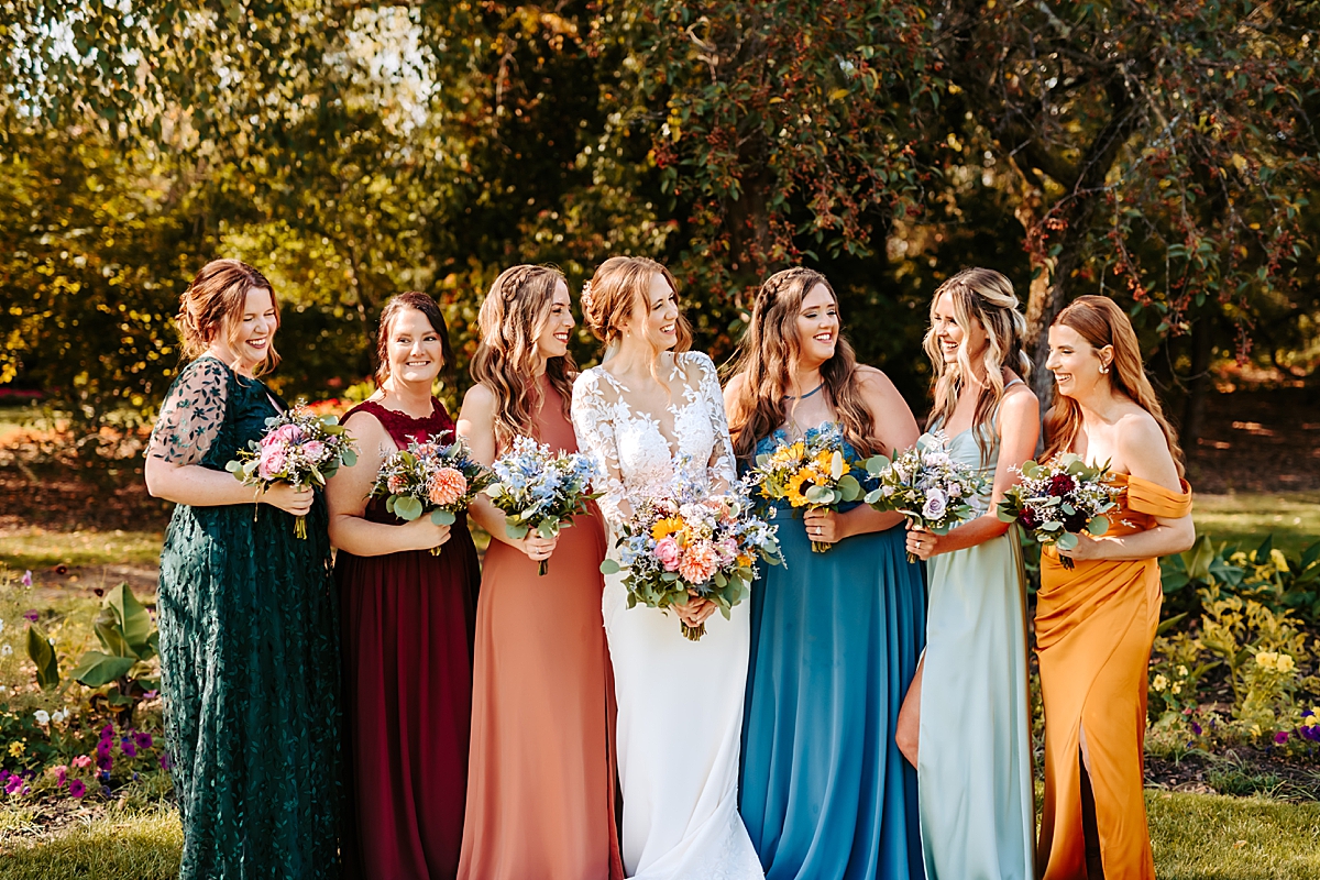 bride smiling with her bridesmaids wearing various jewel tones
