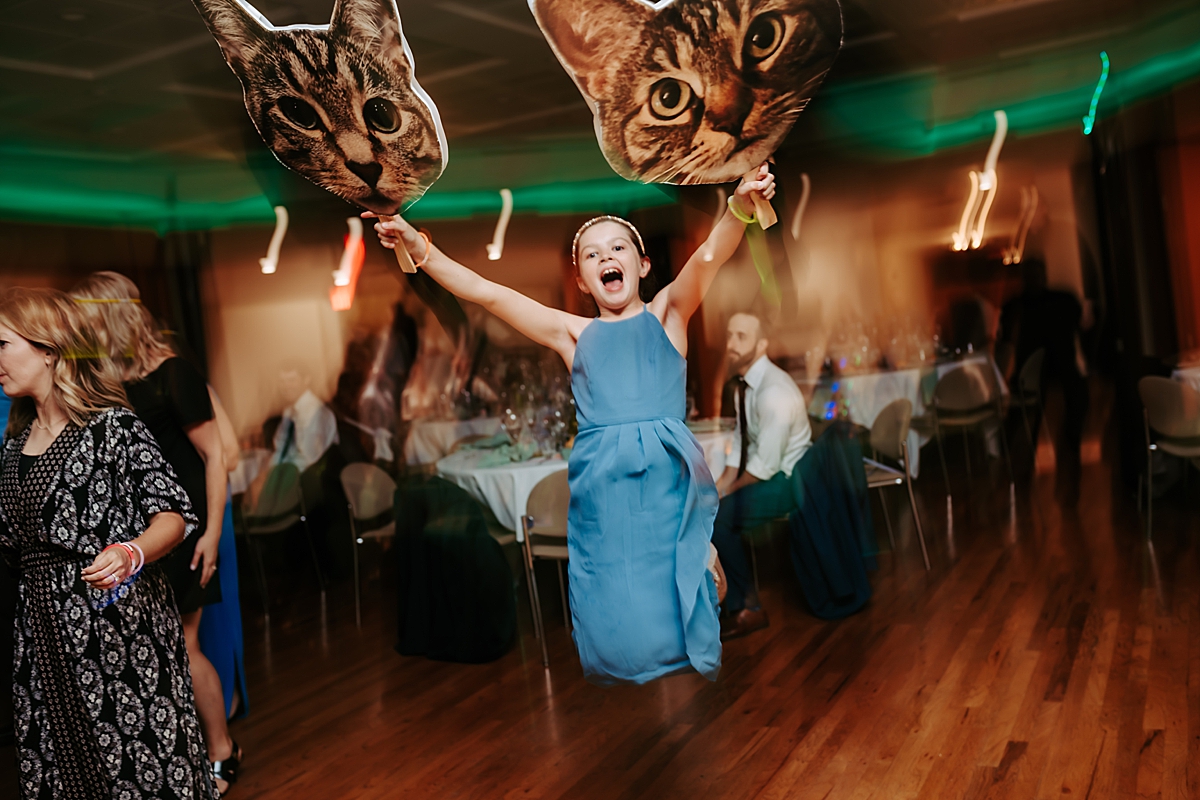 young girl holding cat cutouts on sticks jumping in the air