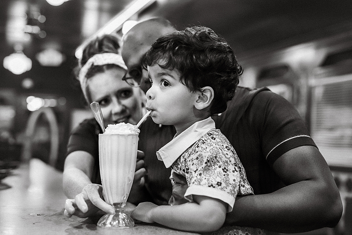 young boy drinking milkshake at diner bar