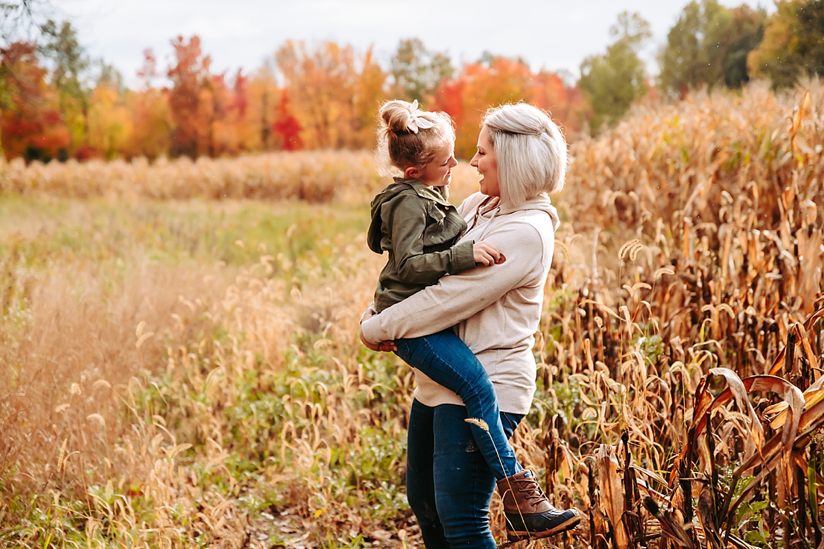 mom holding daughter in her arms in cornfield
