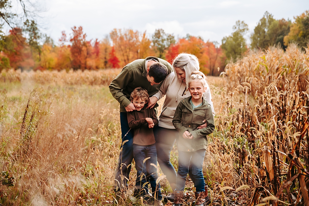 family laughing together in corn field in fall
