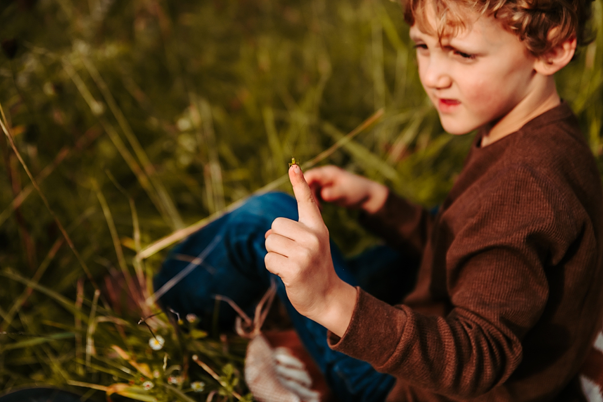 young boy holding grasshopper on his finger