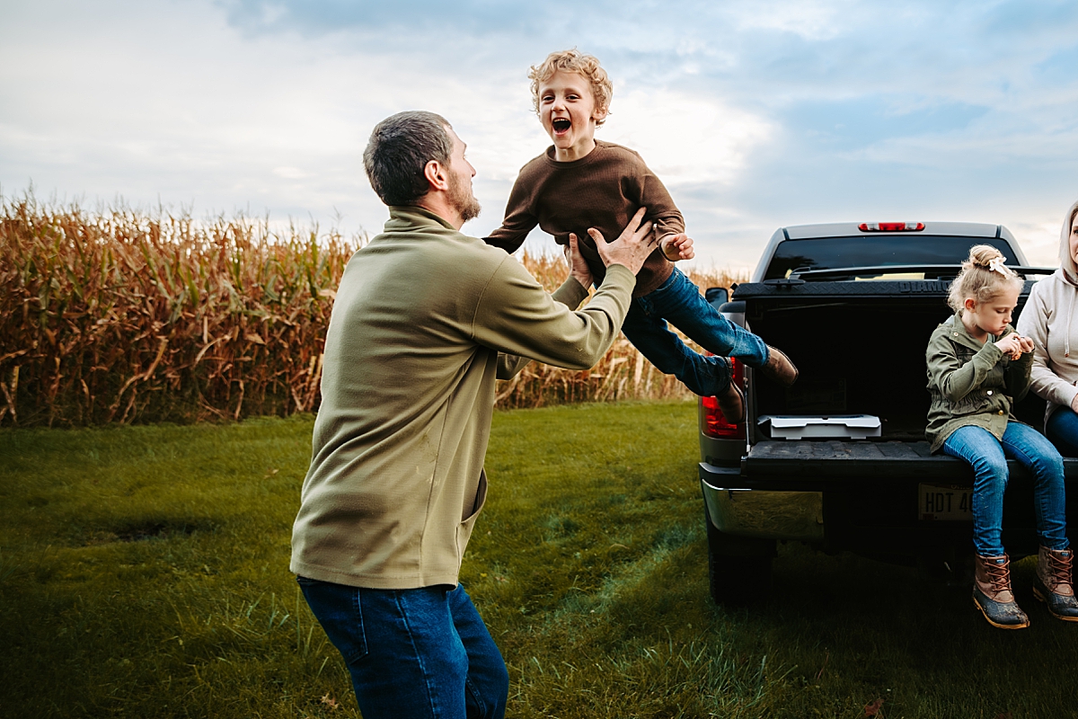 little boy jumping off bed of truck into dad's arms