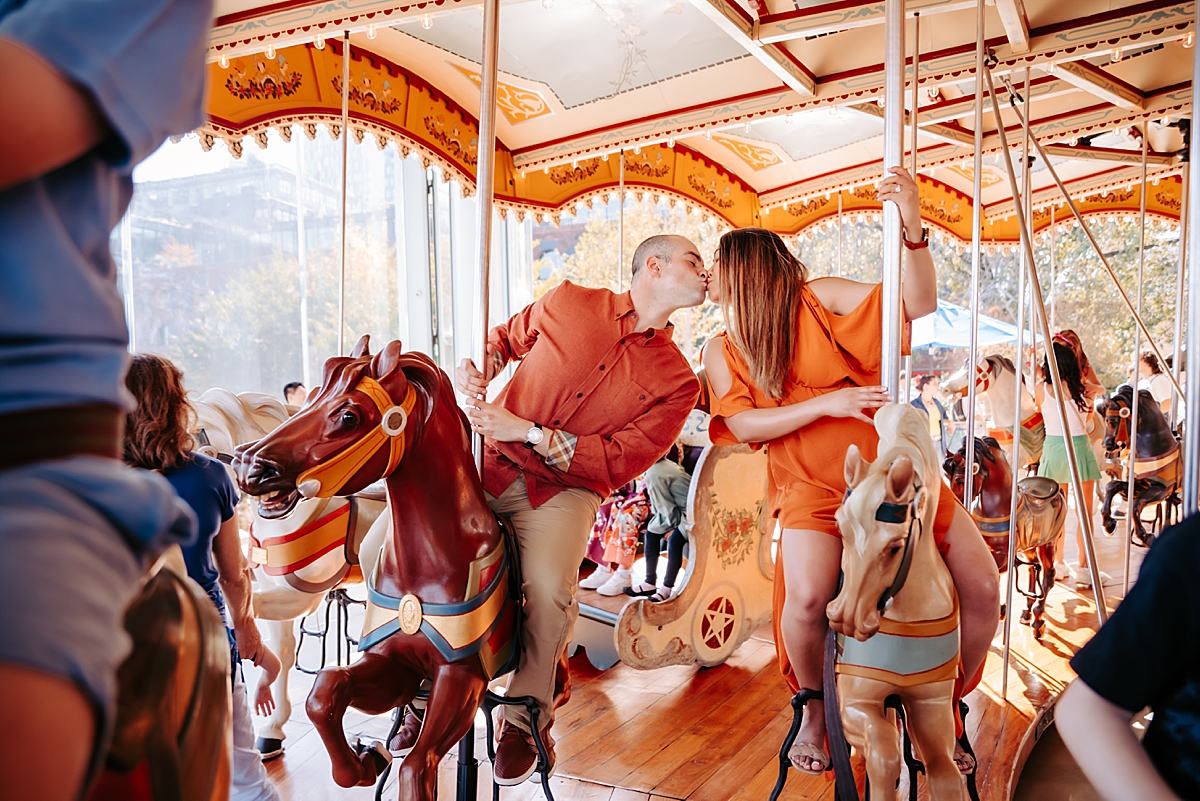 couple riding Jane's Carousel in NYC kissing on horses