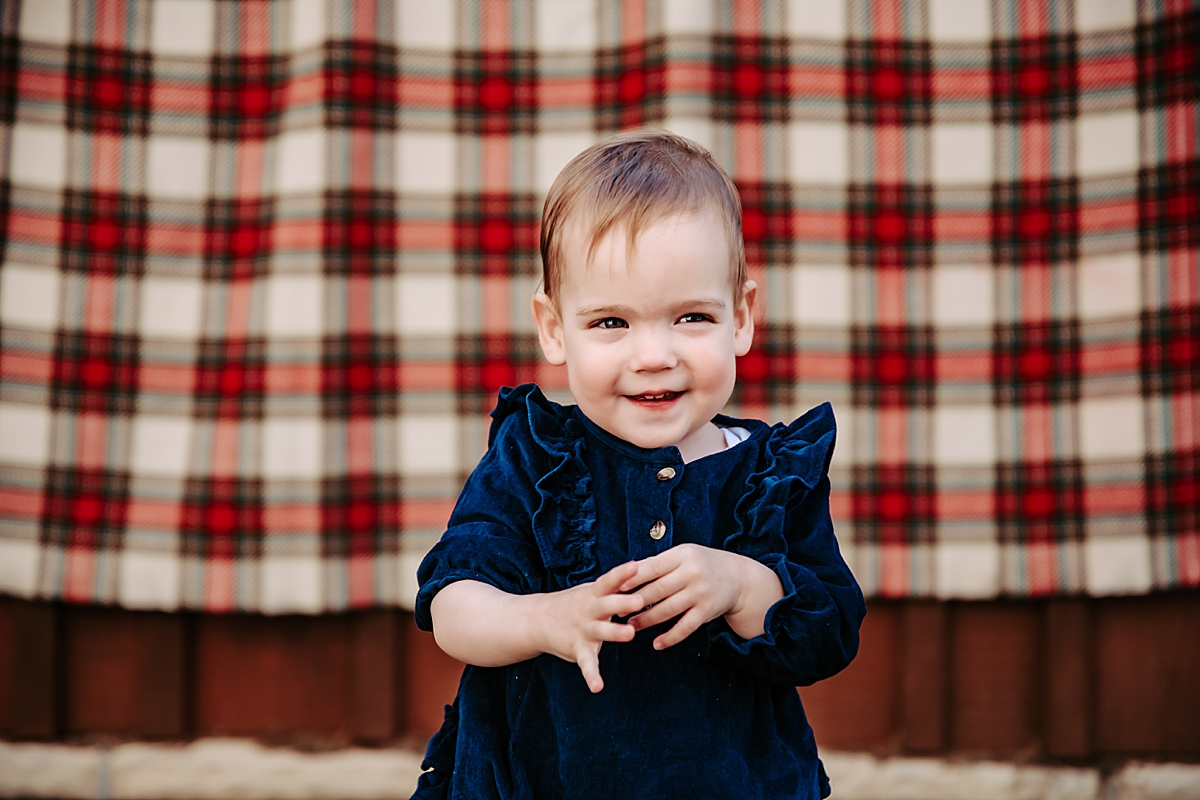 little girl in blue velvet smiling with tartan blanket backdrop
