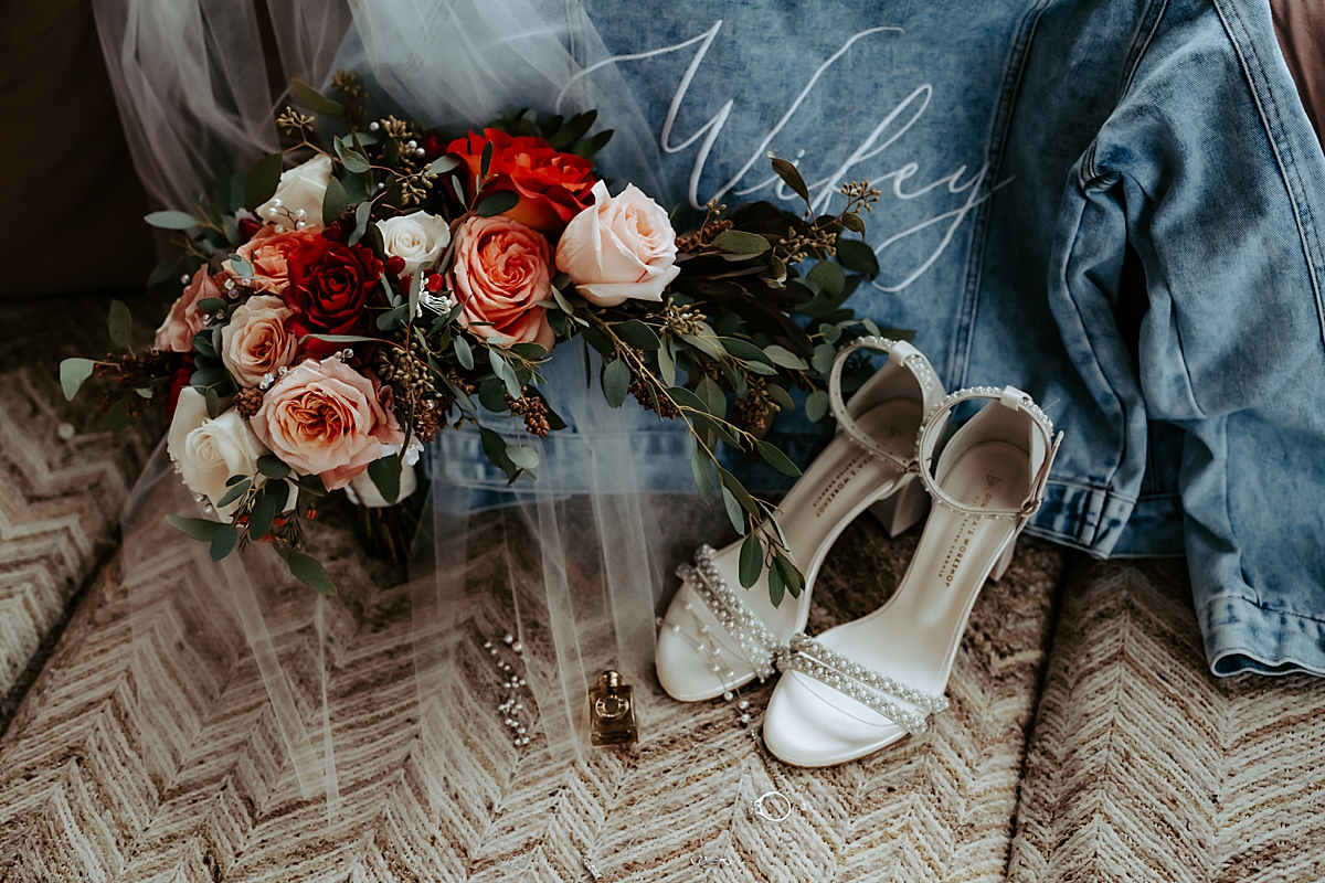 bride's bouquet, shoes, jean jacket, and jewelry laying on couch