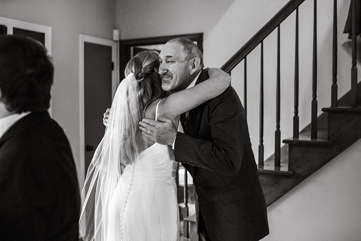 bride's dad hugging his daughter at bottom of staircase