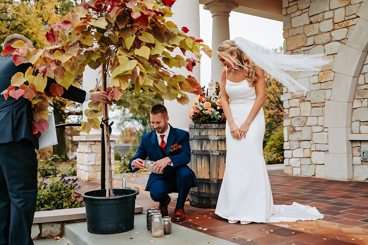 groom pouring jars of dirt into potted tree during wedding ceremony