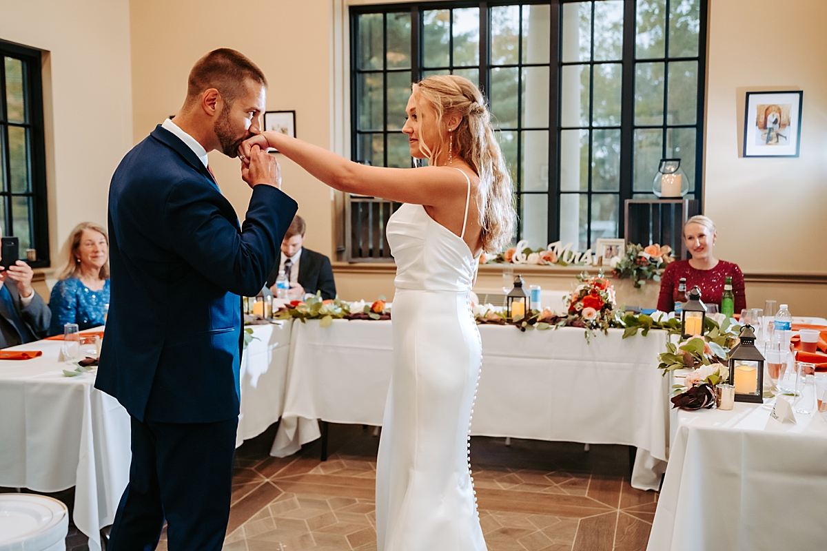 groom kissing bride's hand before first dance at wedding reception