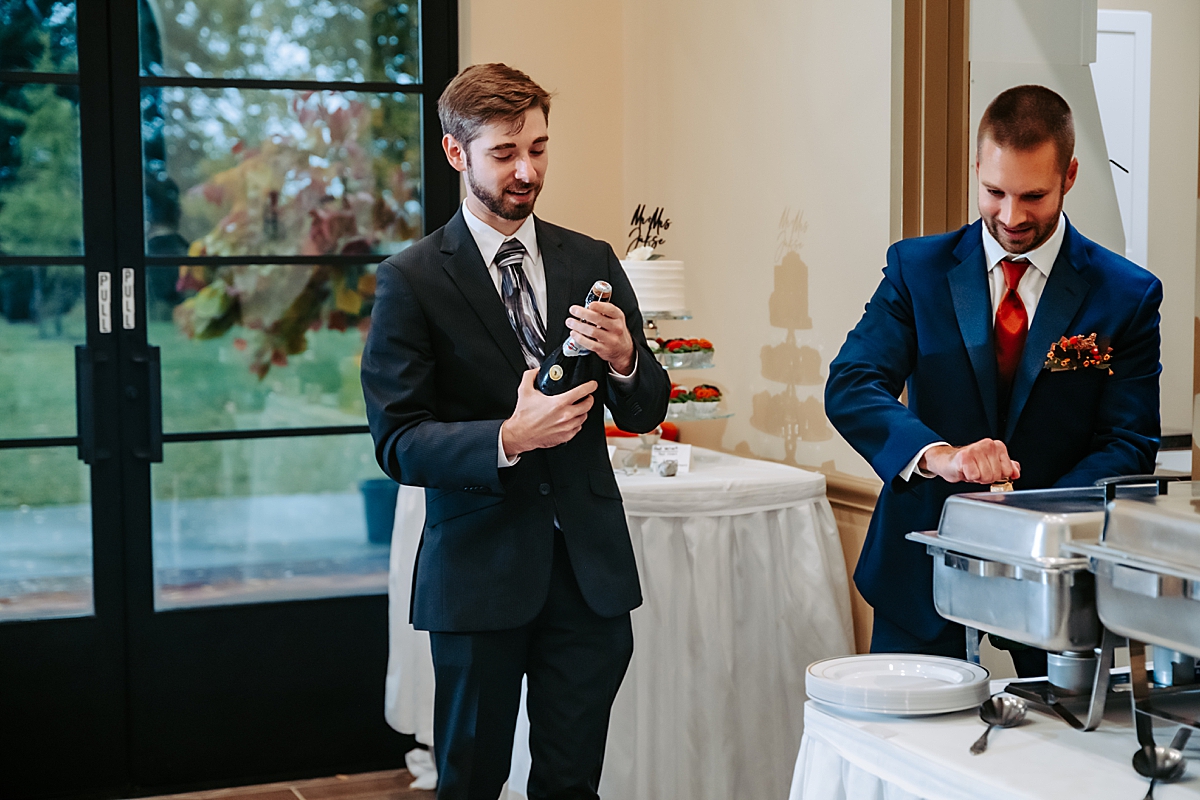 two men opening champagne bottles during wedding dinner