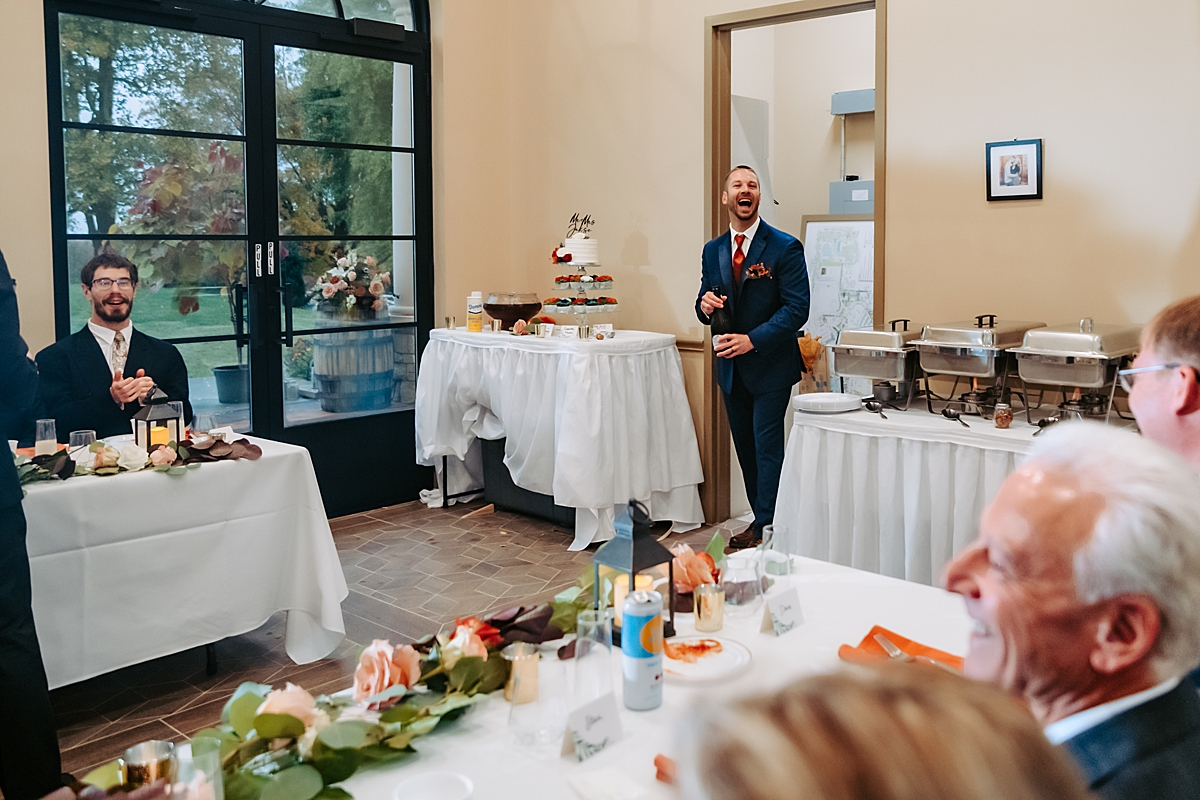 groom laughing opening bottle of champagne