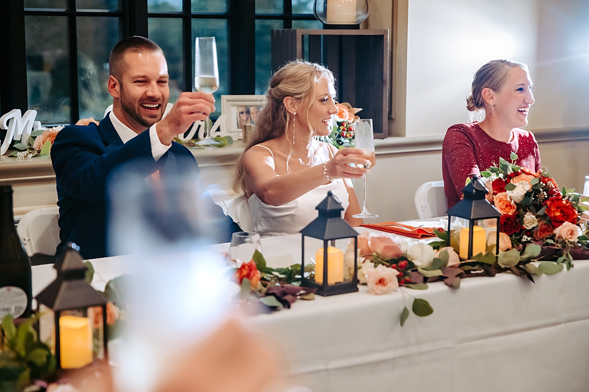bride and groom raising glasses in toast at wedding reception