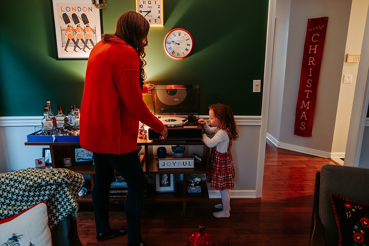 mom helping young girl put record player on turntable in living room