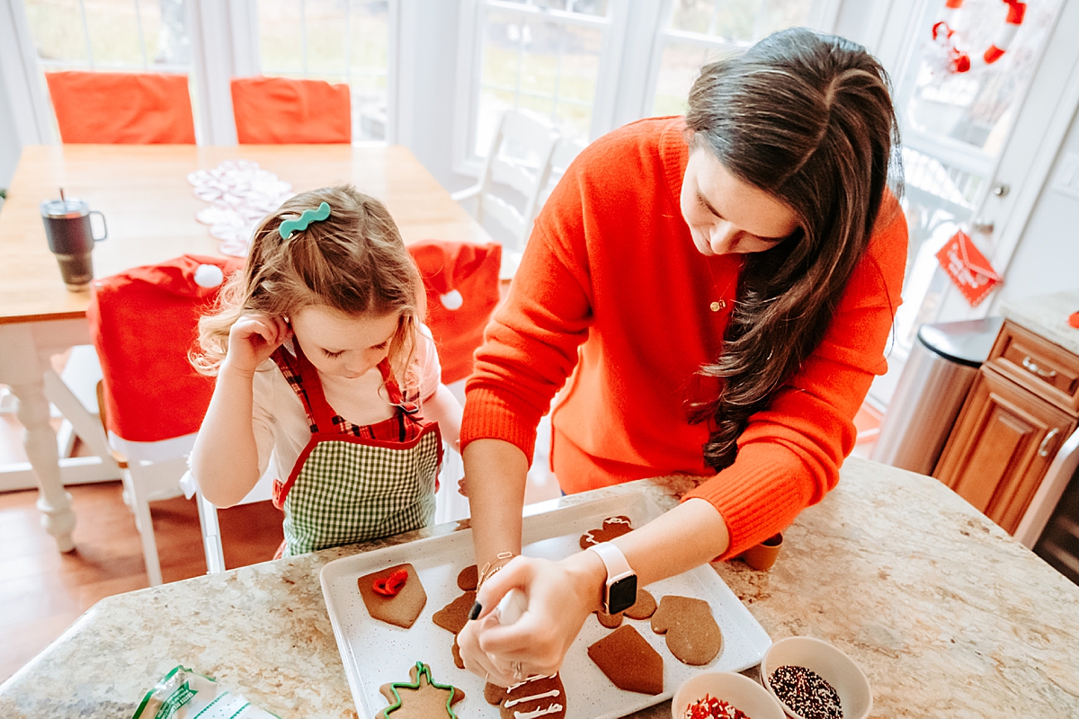 mom and daughter decorating gingerbread cookies with icing