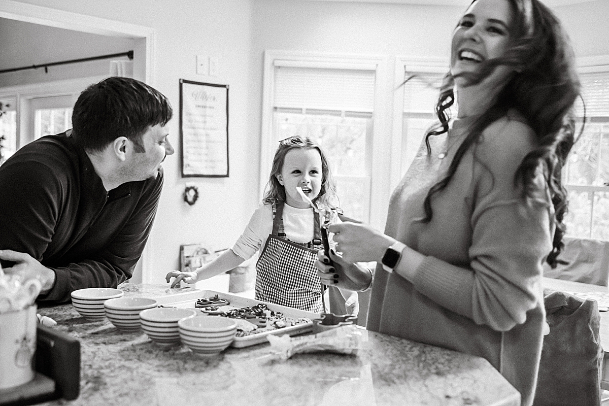 family laughing in kitchen decorating Christmas cookies
