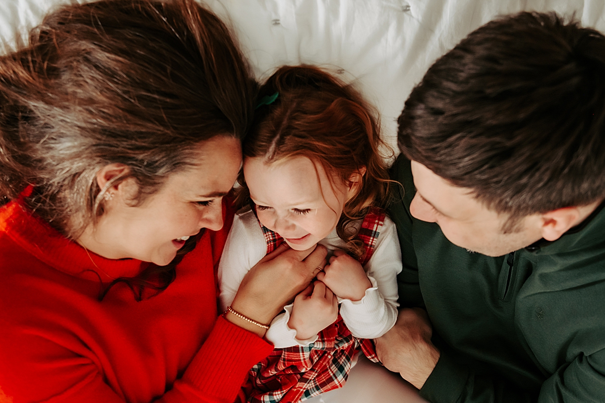 parents and daughter laying on bed laughing