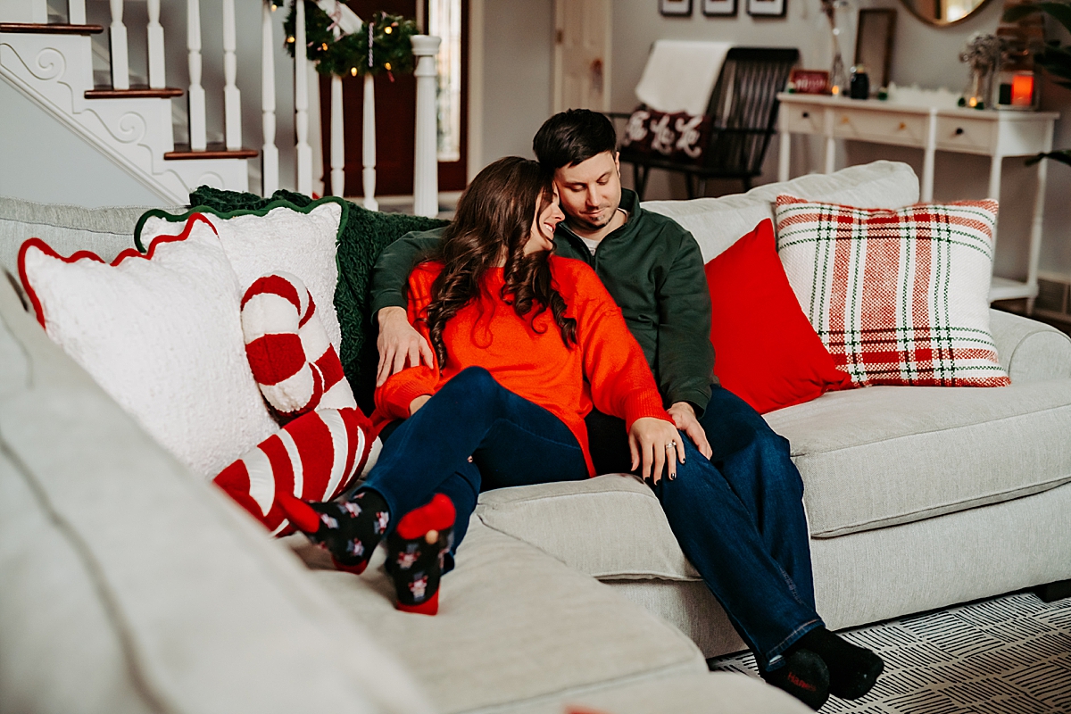 husband and wife snuggling on couch during Christmas lifestyle home session