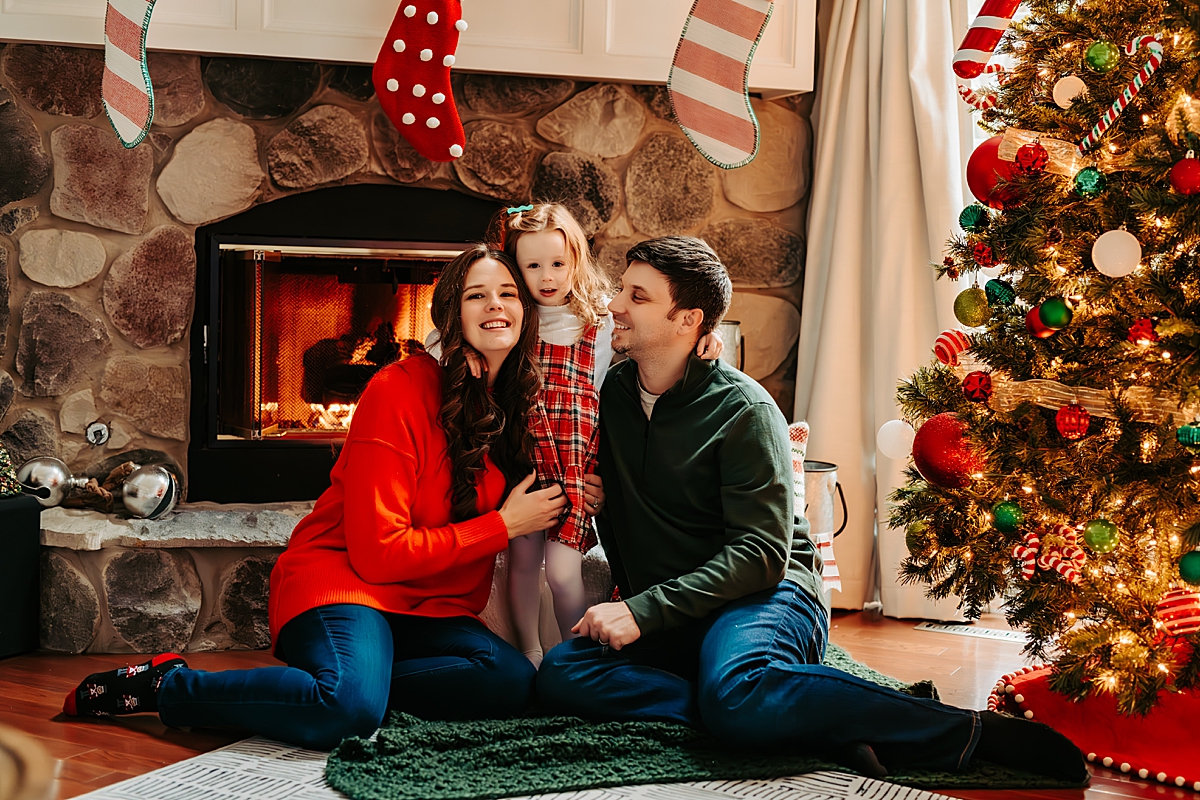 family sitting in front of fireplace next to Christmas tree