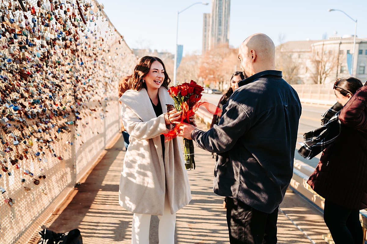 man gives woman bouquet of red roses after proposal in Pittsburgh