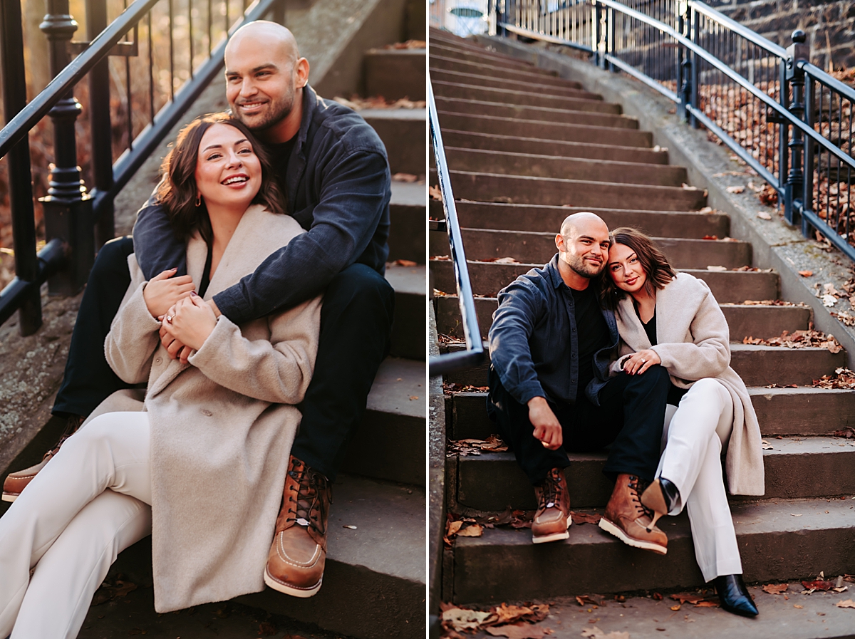 engaged couple sitting on staircase smiling and holding hands
