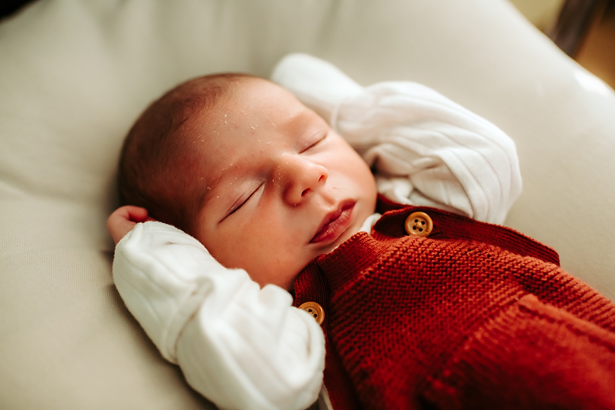 newborn baby boy sleeping in knit overalls