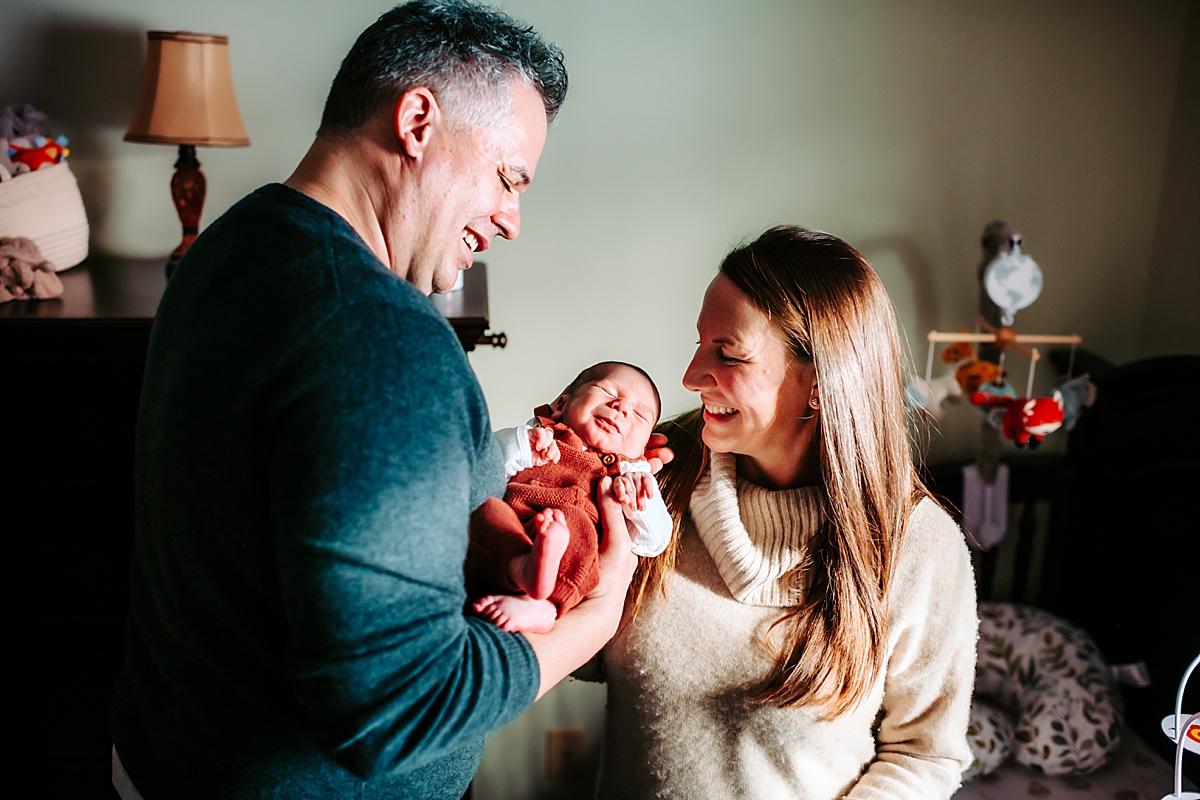 mom and dad smiling at newborn son in nursery