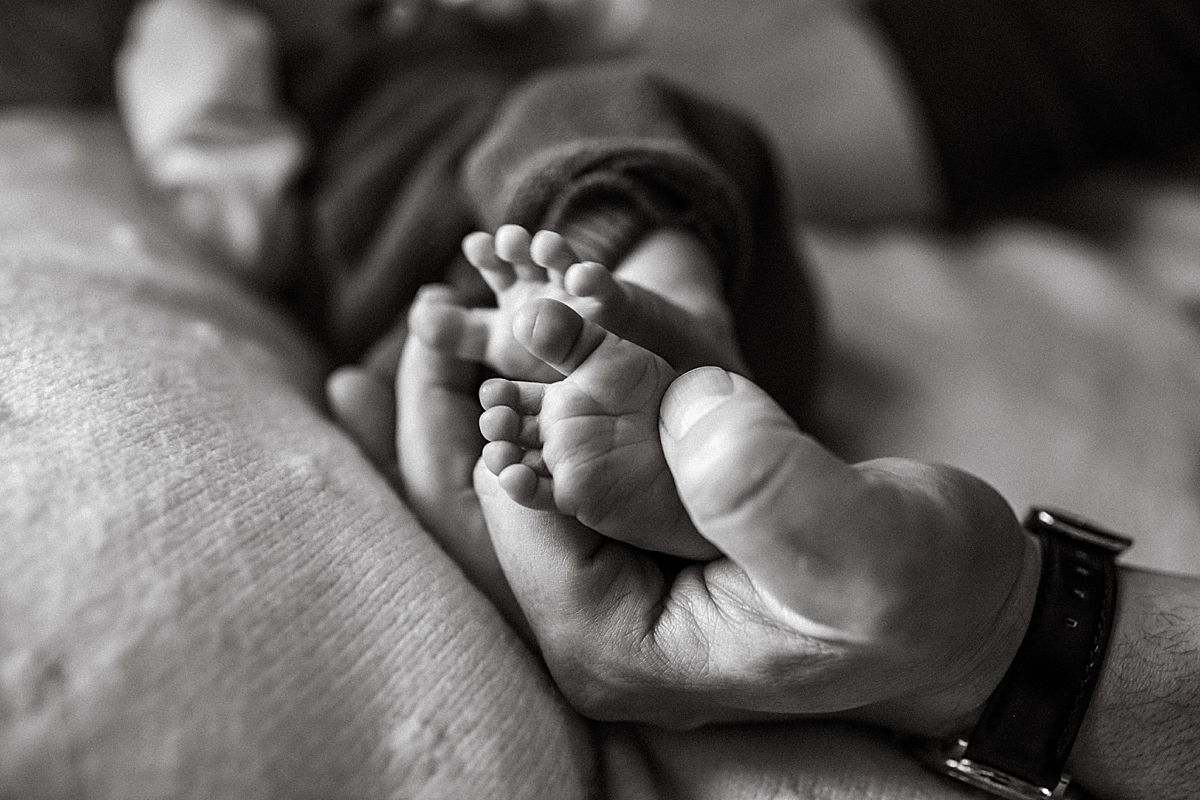 newborn baby's feet in dad's hands