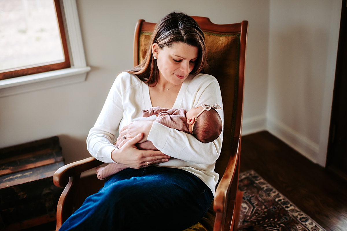mother sitting in rocking chair holding newborn daughter