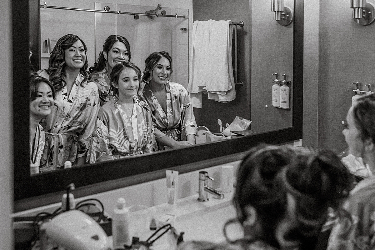 bride and bridesmaids taking selfie in hotel bathroom mirror